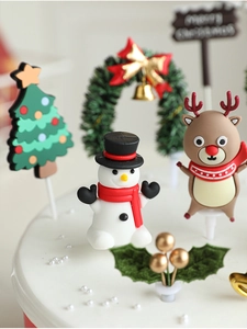 Detail of resin snowman and elk Christmas cake toppers on a white cream cake surface