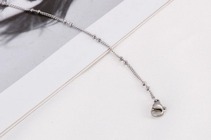 Detailed macro view of silver stainless steel bead chain with a secure lobster clasp