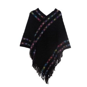 Detail view of ethnic style black knit poncho featuring colorful geometric embroidery and fringe