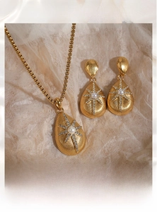 Detail of gold PVD plated drop jewelry set with pearl and zircon star pattern