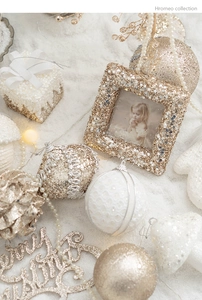 Close-up of golden and white Christmas ornaments with glitter frames and pearls