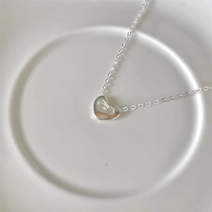 Minimalist 925 sterling silver heart necklace with polished finish on a white plate