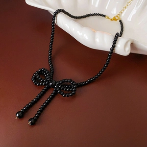 Detail view of black beaded bow necklace with elegant fringes on shell display tray