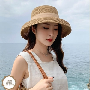 Detail of light coffee straw sun hat featuring elegant ribbon and fine woven texture