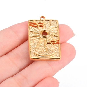 Detailed close-up of a vintage gold rectangular sun pendant with embossed tarot style sun rays