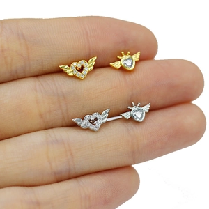 Close-up of heart-shaped winged earrings in gold and silver with sparkling zircon stones