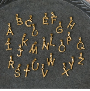 Set of 26 gold 18K plated bamboo style letter charms on a textured display tray