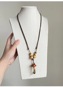 Detail of a handmade mushroom pendant with wooden beads on a brown adjustable cord necklace