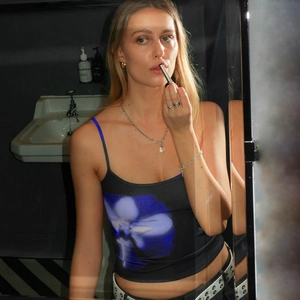 Close-up of slim-fit crop top featuring a vibrant blue orchid print on black fabric