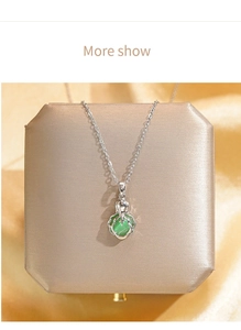 Détail macro d'un collier en acier titane avec un pendentif chou en gemme verte brillante