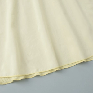 Close-up of yellow cotton dress hem featuring fine texture and detailed stitching work