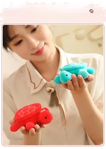 Close-up of cute plush turtle keychain charms in red and green with embroidery details