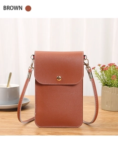 Gros plan d'un sac pour téléphone en cuir marron avec sangle réglable sur table en bois