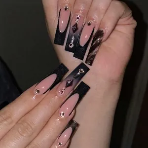 Detail of long coffin press-on nails with nude pink, black matte finish, and rhinestones