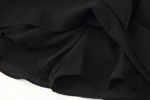Close-up of black ruffled fabric texture with clean hemline and pleated details