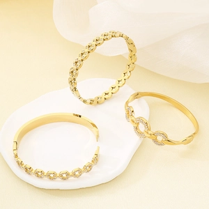 Detail of three luxury gold-plated stainless steel bangles with pavé rhinestones on stone
