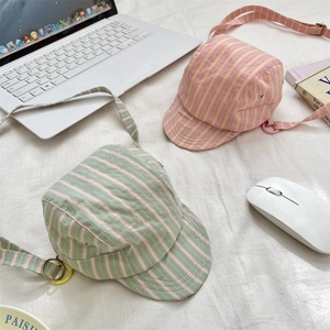 Detail of striped canvas mini bags with adjustable straps on a minimalist white desk