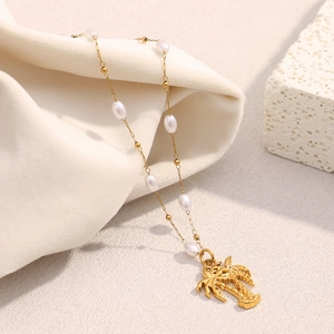 Macro detail of 18K gold plated coconut tree pendant with white pearls on a fine chain