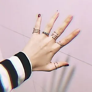 Detail view of silver metal street style rings set worn on fingers in a layered stack