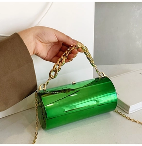 Detail of emerald green cylindrical handbag featuring glossy finish and gold chain handle