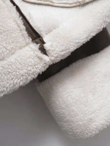 Detailed macro shot of cream faux shearling texture with dark brown leather piping trim