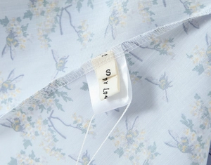 Detail shot of the size S label sewn into a light blue floral halter neck maxi dress