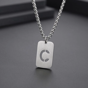 Vue macro d'un pendentif argenté rectangulaire avec la lettre C découpée sur la chaîne