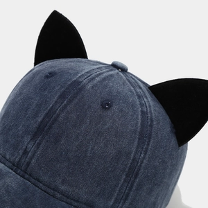 Detailed close-up of velvet cat ears on a navy blue washed denim baseball cap