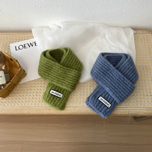 Detail showing thick ribbed knit texture and woven label on wool scarves in green and blue