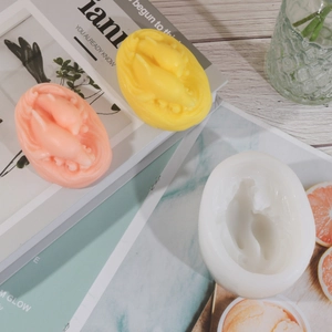 Gros plan de bougies dauphins roses et jaunes à côté d'un moule en silicone souple