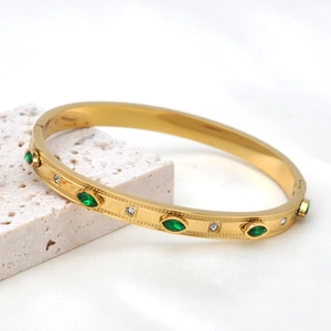 Detailed macro of gold hexagram bracelet with green emeralds and small diamonds
