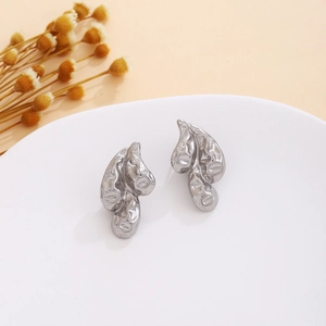 Detail of silver heart earrings with lava texture and crinkled design on white tray