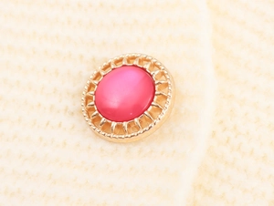 Macro detail of retro pink pearl bead and golden woven metal frame on knit sweater