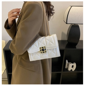 Detail of white quilted handbag with gold chain strap and elegant metallic buckle closure