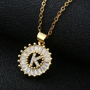 Gros plan du pendentif doré lettre K avec zircons baguette et motif rayon de soleil