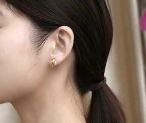 Détail d'une boucle d'oreille créole dorée avec perle portée par un mannequin