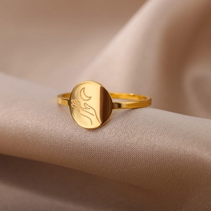 Detail of 18K gold stainless steel ring with moon engraving on beige silk fabric