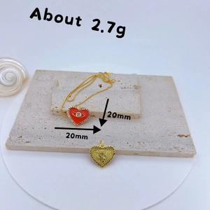Macro view of gold-plated red heart pendant with eye motif and colorful cubic zirconia