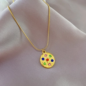 Macro view of gold plated titanium necklace with colorful stones on satin background
