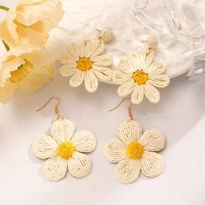 Detail of handmade raffia flower earrings featuring ivory petals and yellow centers
