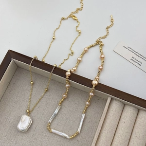 Detail of baroque pearl necklace set with gold chain on a wooden jewelry display