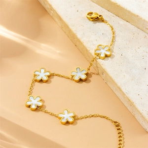 Elegant gold titanium steel bracelet with five white shell flower charms on stone surface