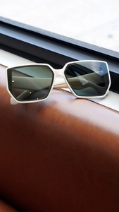 Close-up of stylish white oversized square sunglasses on a brown leather surface