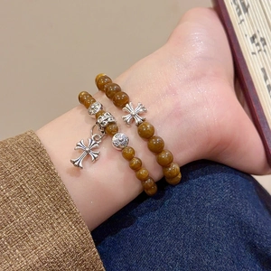 Gros plan de bracelets rétro à deux couches avec pendentif croix en argent sur le poignet
