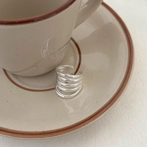 Detailed shot of S925 sterling silver multilayer ring on a minimalist ceramic plate