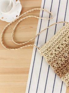 Handmade woven gradient straw crossbody bag in beige and brown on a wooden table