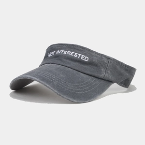 Detail of washed grey sun visor with NOT INTERESTED embroidery and textured cotton fabric