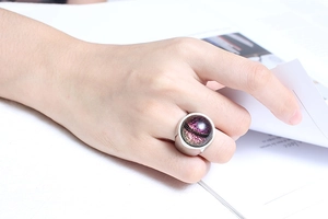 Close-up of a women's silver ring with purple stellar glass dome on a model's hand