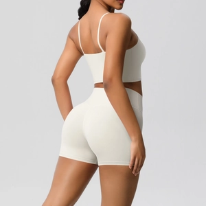 Detail view of cream high-waisted yoga shorts and strap top showing athletic fit and lifting