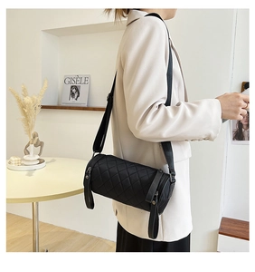 Detailed macro view of black quilted cylindrical crossbody bag with rhombus stitching